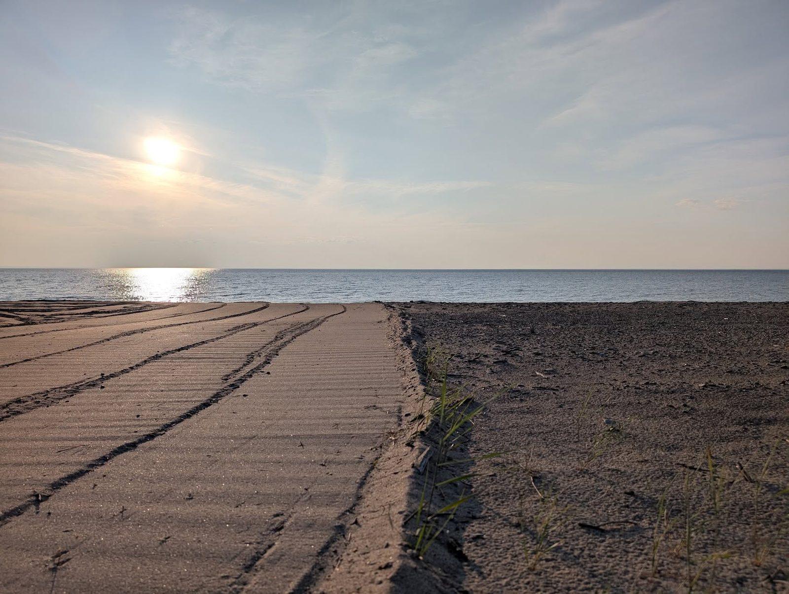 Démarcation nette au coucher du soleil : à gauche le sable tamisé, fin et strié ; à droite le sable brut, foncé et parsemé de cailloux.