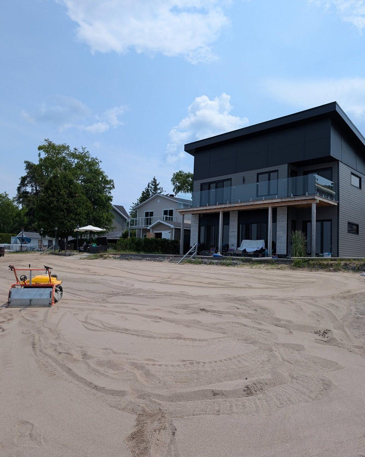 Grande plage privée tamisée devant une résidence au bord du lac, avec l'équipement Capitaine Plage stationné sur le sable.